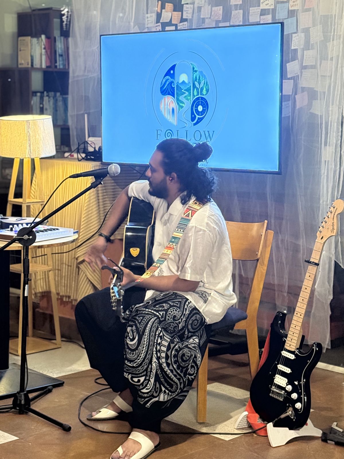 Nandan performing with guitar beside the screen